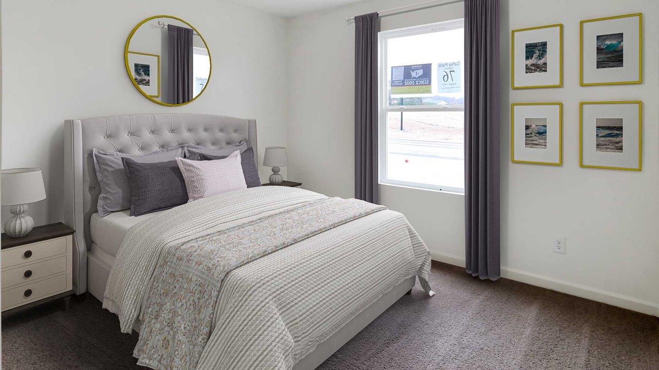 A cozy bedroom featuring a bed, a mirror, and a window allowing natural light to enter the space.