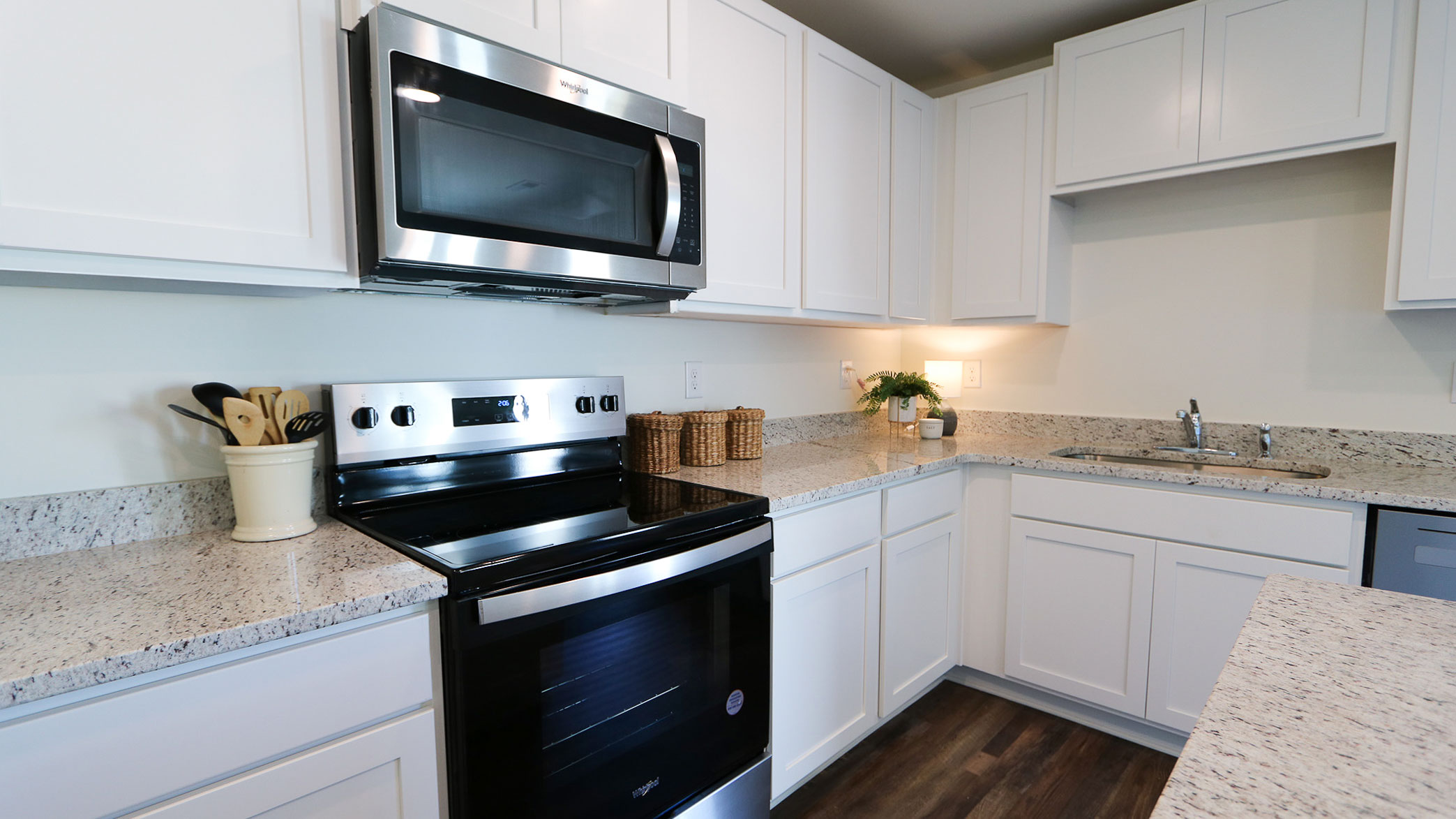 An alternate view of a kitchen with sleek white cabinets and stainless-steel appliances, highlighting its contemporary design.