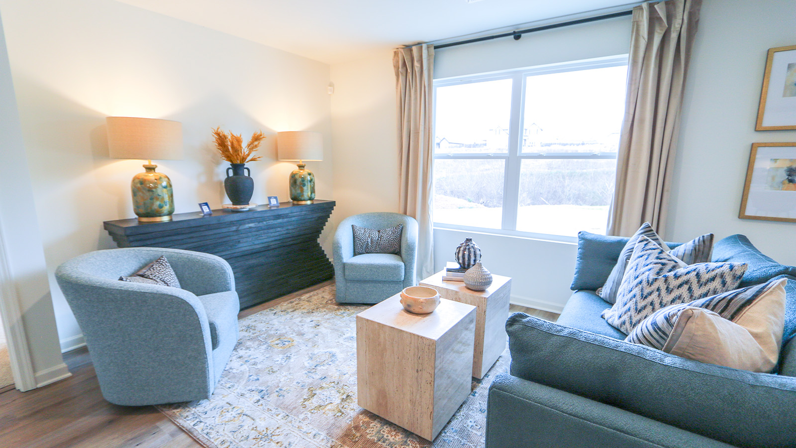 A spacious living room that features a couch, two poofs, a coffee table, a media consol and an accent chair.