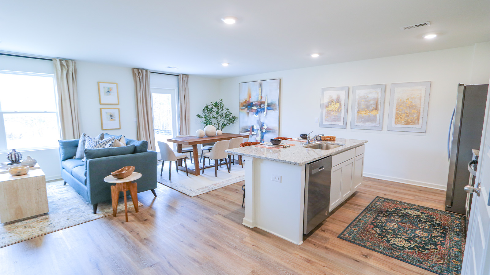The open concept kitchen connects seamlessly to the dining room and the living room, creating a spacious and integrated living area. It boasts an oversized kitchen island with seating for three, complemented by sleek stainless-steel appliances, white cabinets, and a convenient pantry.