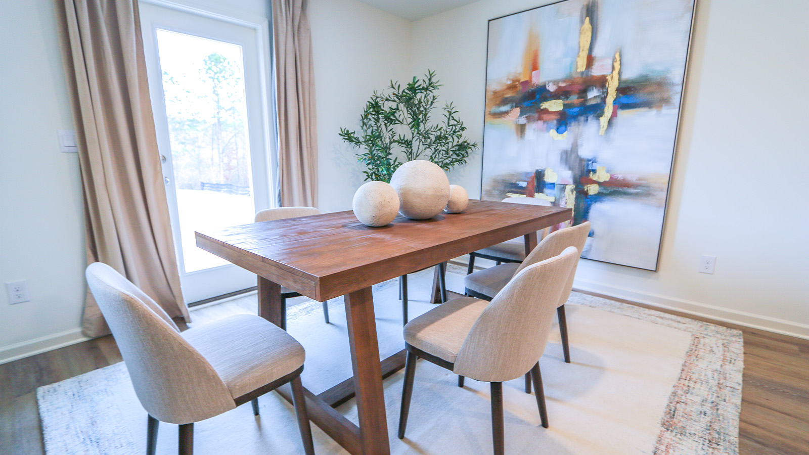 The open concept kitchen is designed to seamlessly connect with the dining room and the living room. It showcases an oversized kitchen island equipped with three barstools for seating. The kitchen is furnished with stainless steel appliances, white cabinets, and a pantry for storage.