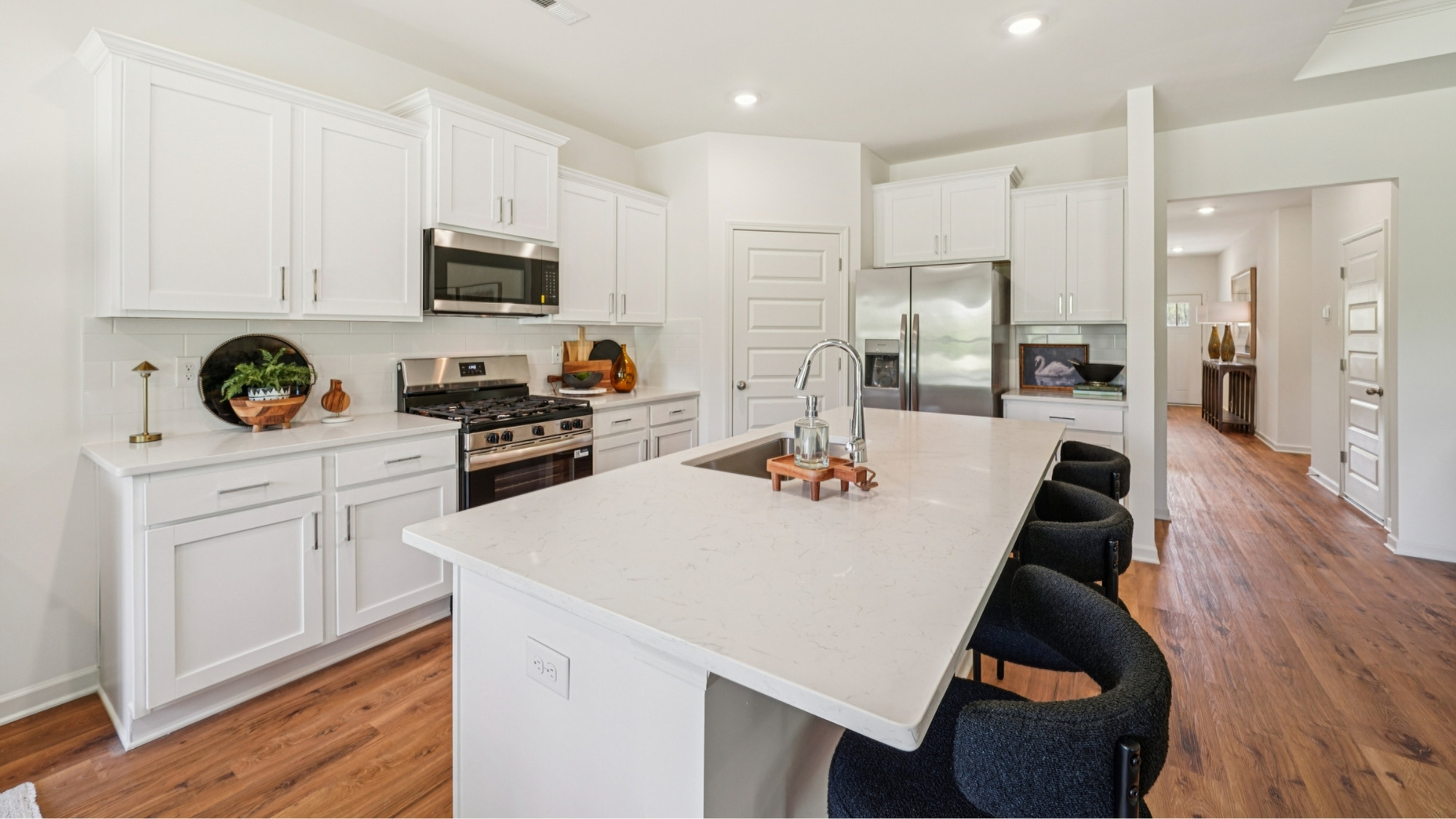 The kitchen is a spacious open concept area with stainless steel appliances. It includes an oversized kitchen island with barstools for seating and food preparation. Additionally, there is a convenient walk-in pantry for storage.