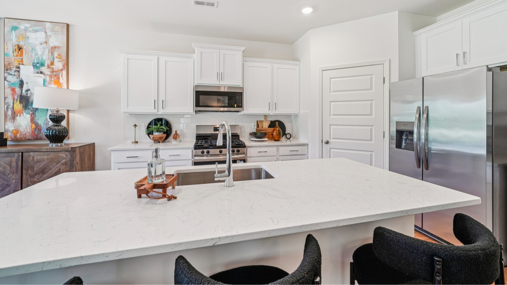 The kitchen is a spacious open concept area with stainless steel appliances. It includes an oversized kitchen island with barstools for seating and food preparation. Additionally, there is a convenient walk-in pantry for storage.