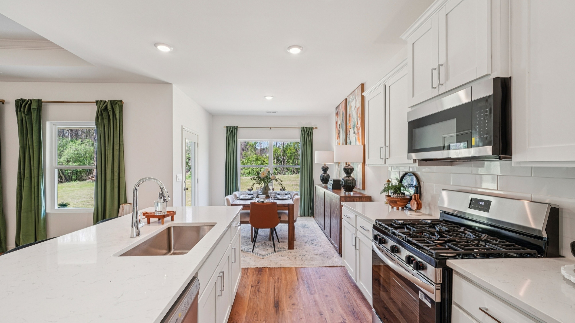 The kitchen is a spacious open concept area with stainless steel appliances. It includes an oversized kitchen island with barstools for seating and food preparation. Additionally, there is a convenient walk-in pantry for storage.
