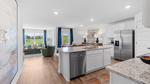 The kitchen is a spacious open concept area with stainless steel appliances. It includes an oversized kitchen island with barstools for seating and food preparation. Additionally, there is a convenient walk-in pantry for storage.