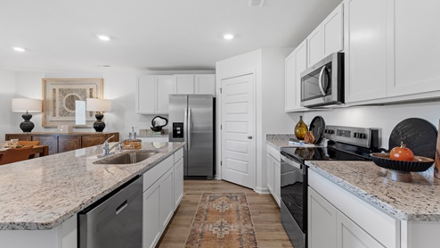 The kitchen is a spacious open concept area with stainless steel appliances. It includes an oversized kitchen island with barstools for seating and food preparation. Additionally, there is a convenient walk-in pantry for storage.