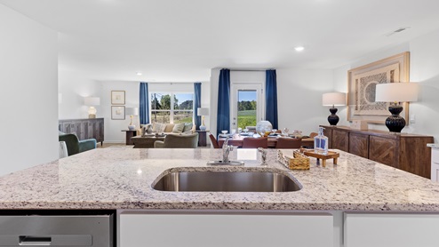 The kitchen is a spacious open concept area with stainless steel appliances. It includes an oversized kitchen island with barstools for seating and food preparation. Additionally, there is a convenient walk-in pantry for storage.