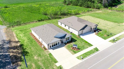 High point model home featuring light brown brick, fresh sod and a bright blue sky