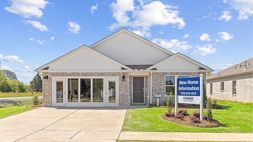 High point model home featuring light brown brick, fresh sod and a bright blue sky
