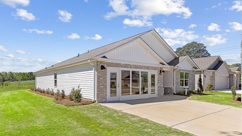 High point model home featuring light brown brick, fresh sod and a bright blue sky