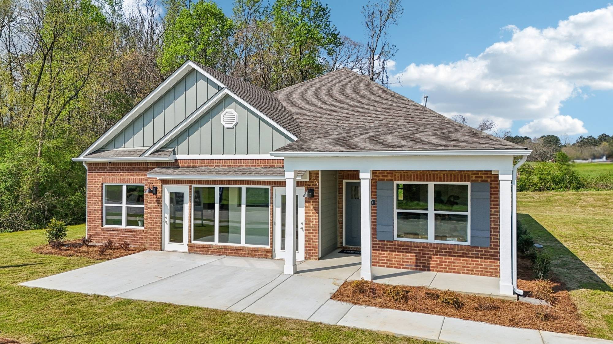 High point model home featuring light brown brick, fresh sod and a bright blue sky