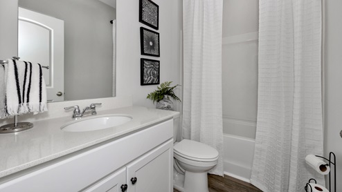 Secondary bathroom with painted cabinets and quartz countertops