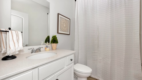 Secondary bathroom with painted cabinets and quartz countertops