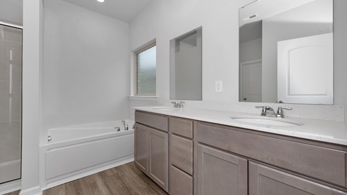 Primary bath with stained cabinets and quartz countertops