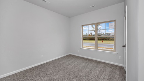 Secondary bedroom with carpet and window