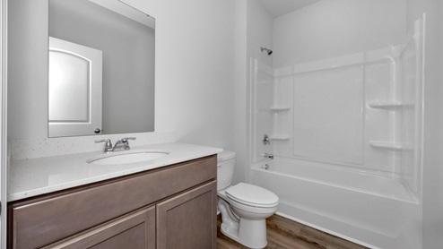 Secondary bathroom with stained cabinets and quartz countertops