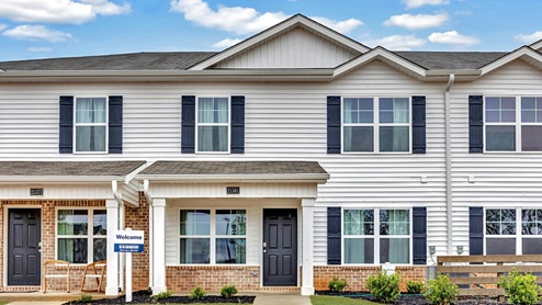 two story townhome with vinyl and brick and two car garage