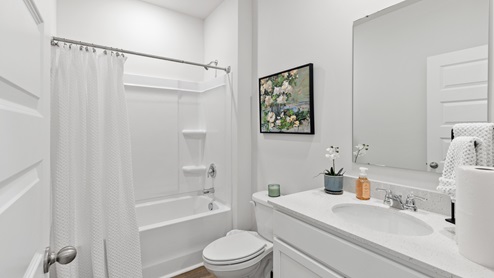 Secondary bathroom with painted cabinets and quartz countertops