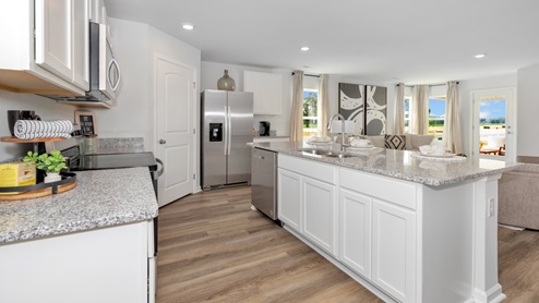 Kitchen island with painted cabinets and stainless steel appliances