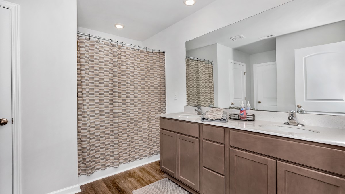 Primary bath with stained cabinets and quartz countertops