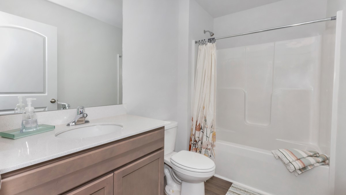 Secondary bathroom with stained cabinets and quartz countertops