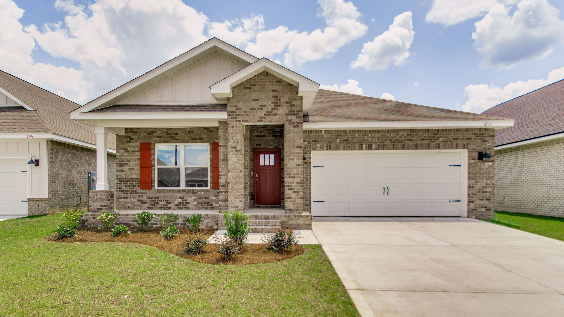 Exterior elevation of new red brick home with white trim and a two-car garage