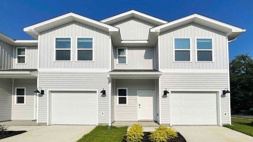 Exterior elevation of two-story new townhome with white siding and double windows.