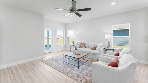 Large living room with several windows for natural lighting and direct access to backyard through glass door.