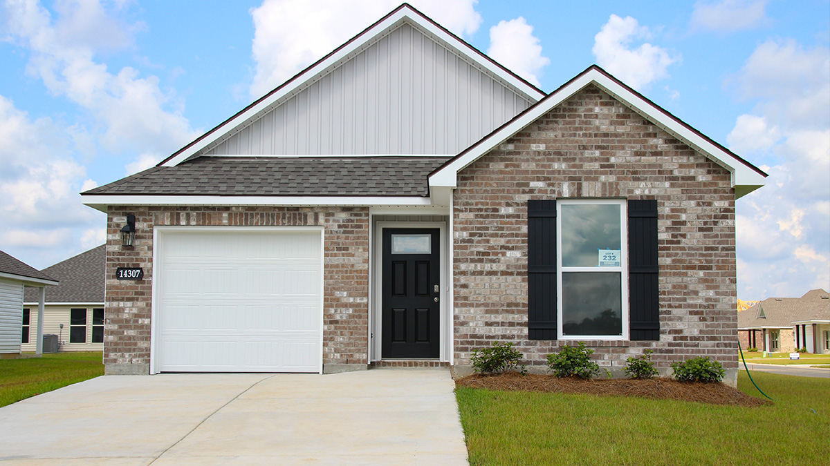 Single-story home with brown brick. Black glass front door with black shutters and white trim.