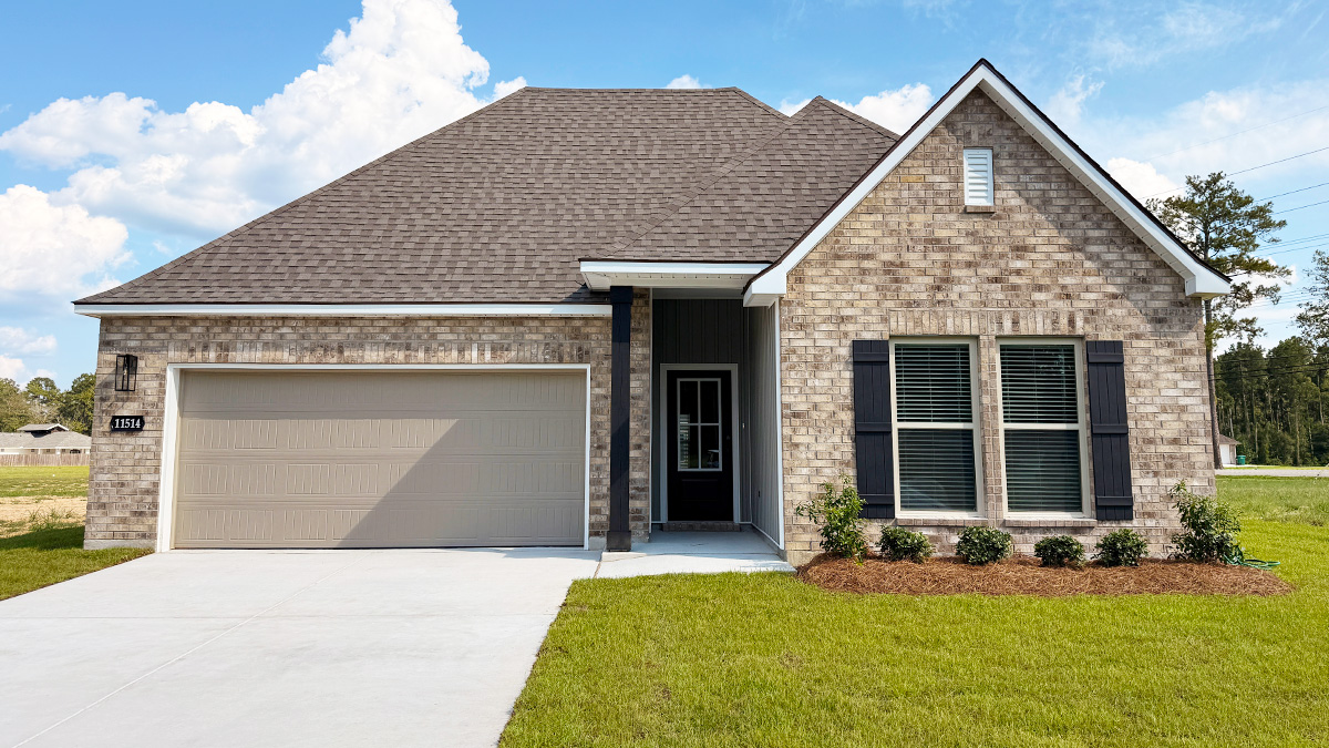 Single-story home with brown brick. Black glass front door with brown shutters and white trim.