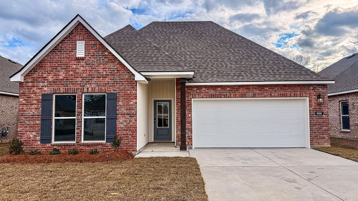 single-story home with red brick and black front door and shutters with tan vinyl siding and two-car garage