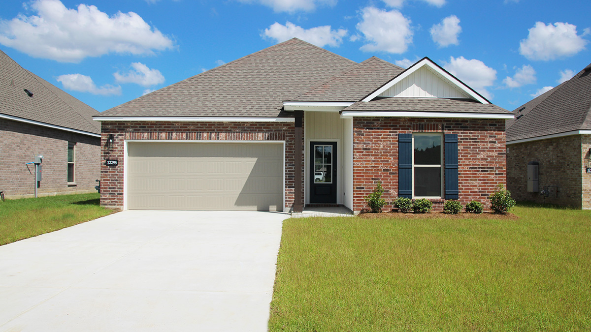 Single-story home with red brick. Navy blue glass front door with navy blue shutters and tan trim.