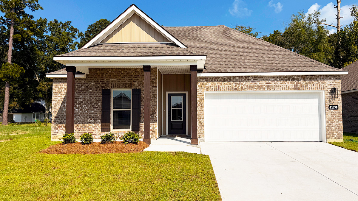 Single-story home with brown brick. Black glass front door with black shutters and white trim.