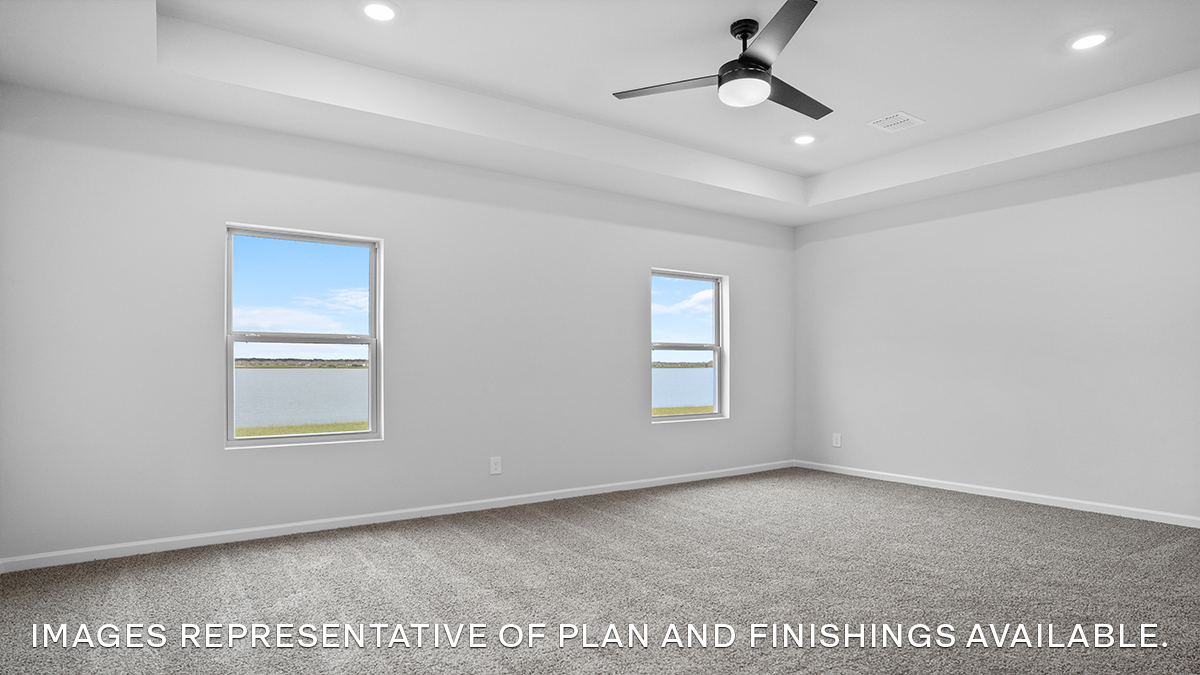 Large primary bedroom with dual windows overlooking the backyard