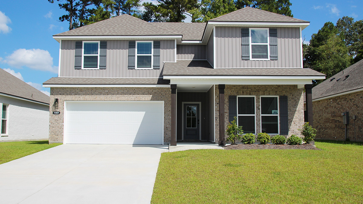 two-story home with tan brick and light gray vinyl siding with gray front door and shutters with porch and two-car garage