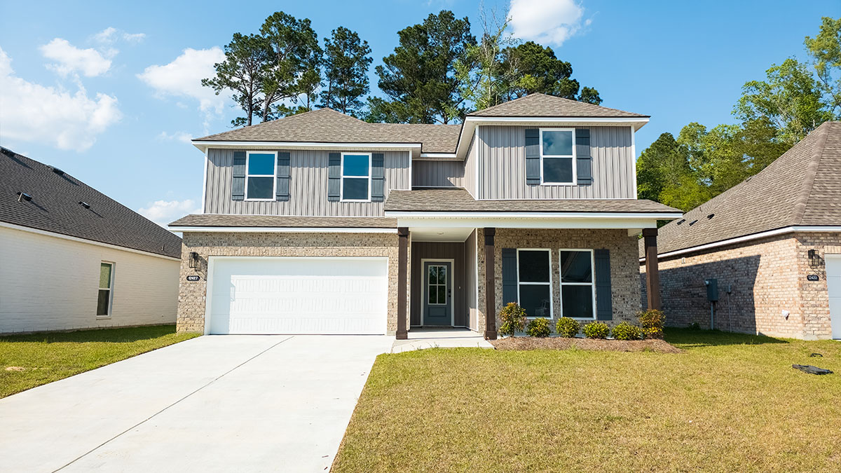double-story home with tan brick and light gray vinyl siding with gray front door and shutters with porch and two-car garage