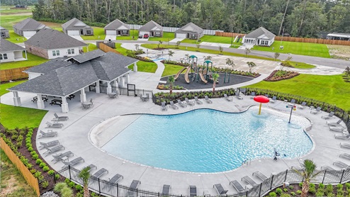 resort-style pool with clubhouse with white siding and black accents and a green playground with swings