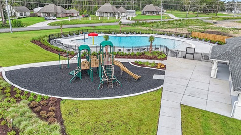 green playground with swings and an resort-style pool
