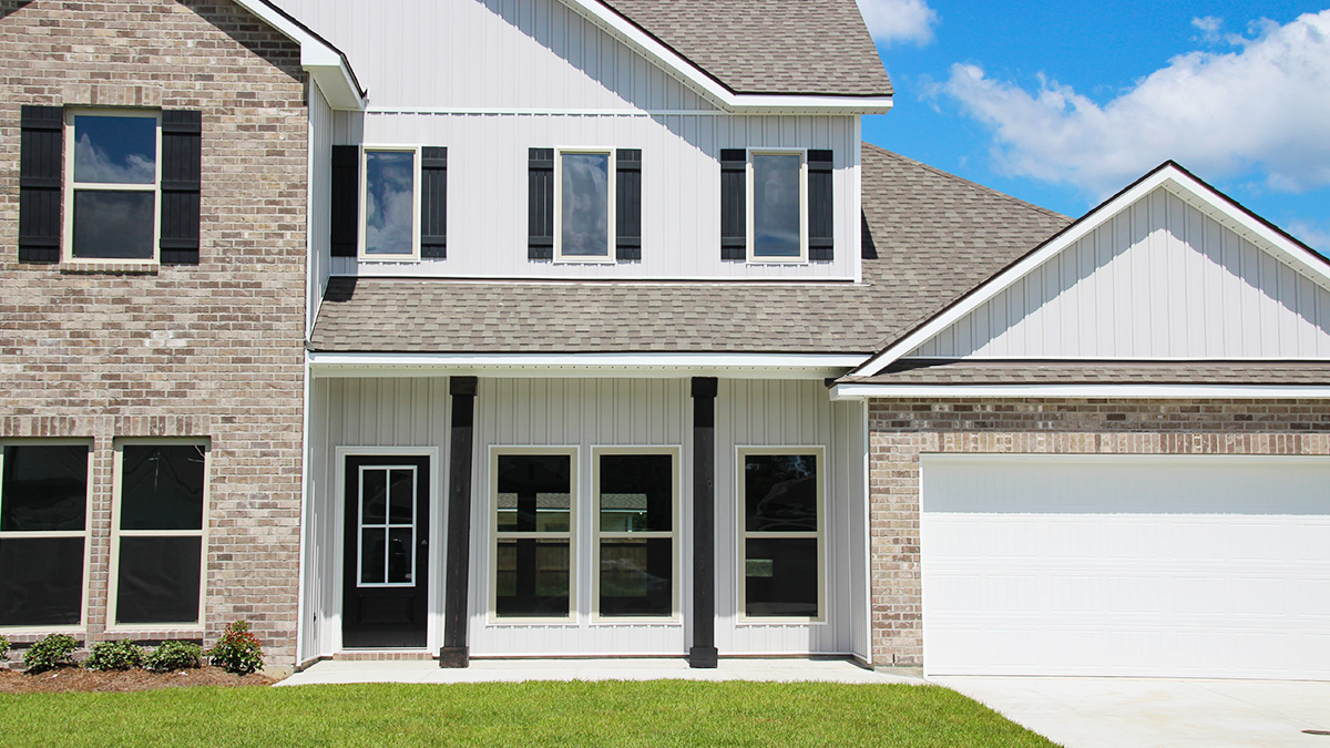 Two-story home with white hardie vinyl and brown brick. Black glass front door with black shutters and white trim.