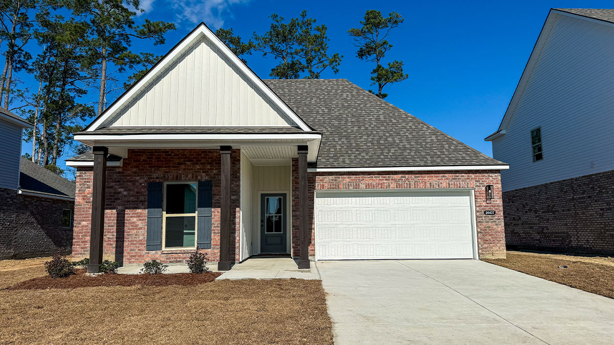 single-story home with red brick with tan vinyl siding with black front door and shutters with porch and two-car garage