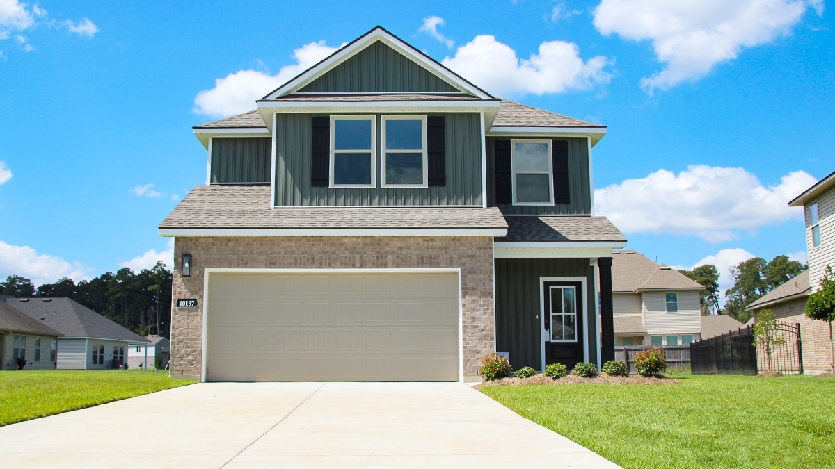 Two-story home with green hardie vinyl and brown brick. Black glass front door with black shutters and white trim.