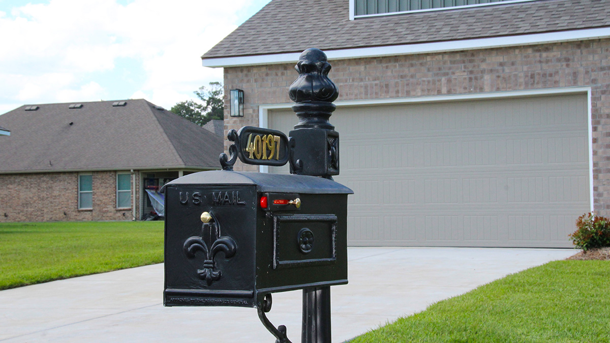 Two-story home with green hardie vinyl and brown brick. Black glass front door with black shutters and white trim.