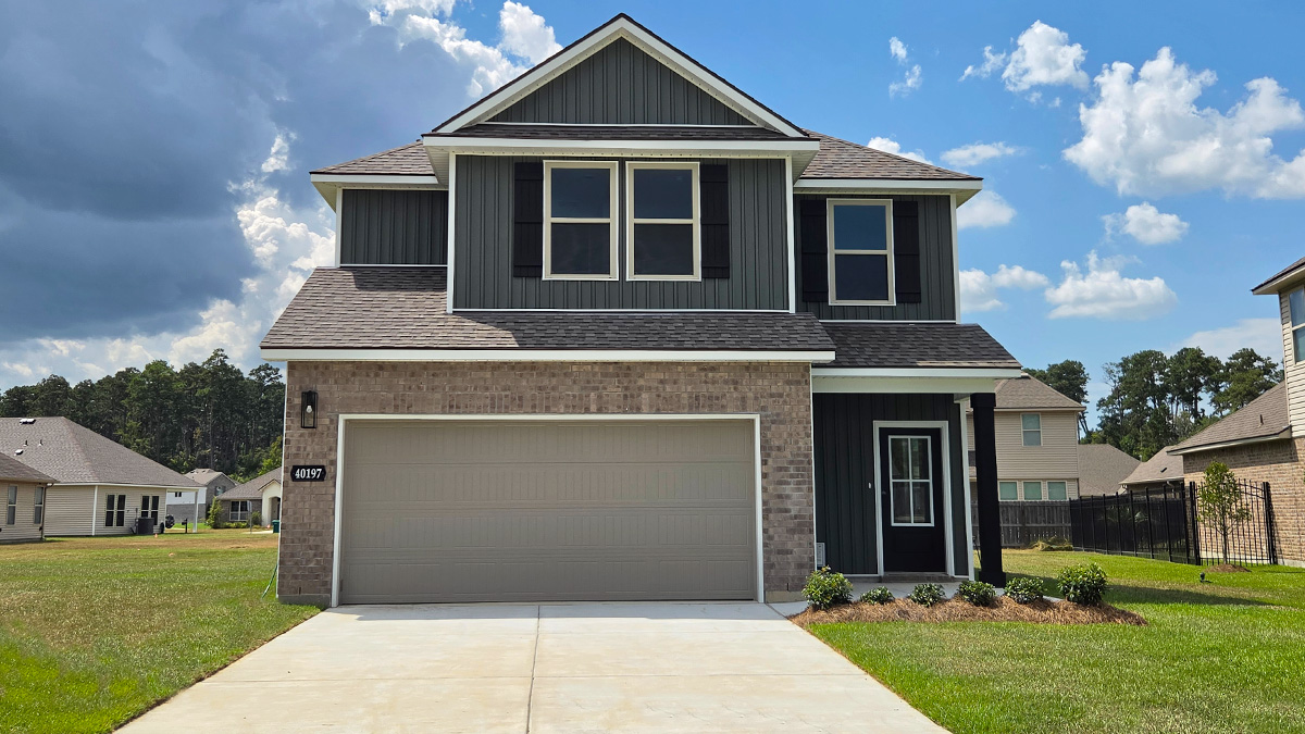 Two-story home with green hardie vinyl and brown brick. Black glass front door with black shutters and white trim.