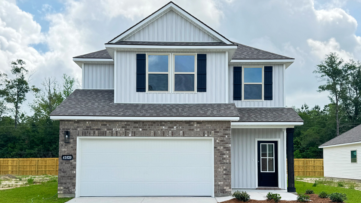 Two-story home with grey hardie vinyl and brown brick. Navy blue glass front door with navy blue shutters.