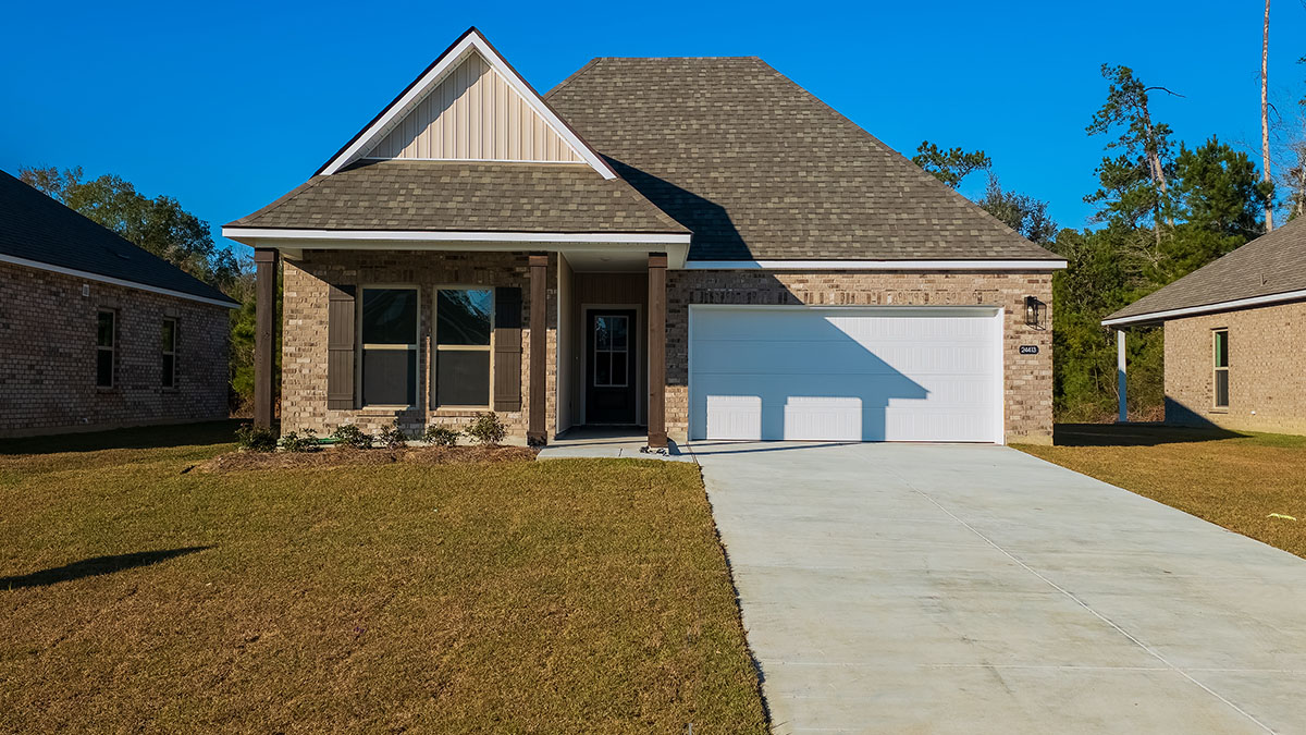 singe-story home with tan brick and tan vinyl siding with porch with brown front door and shutters and two-car garage