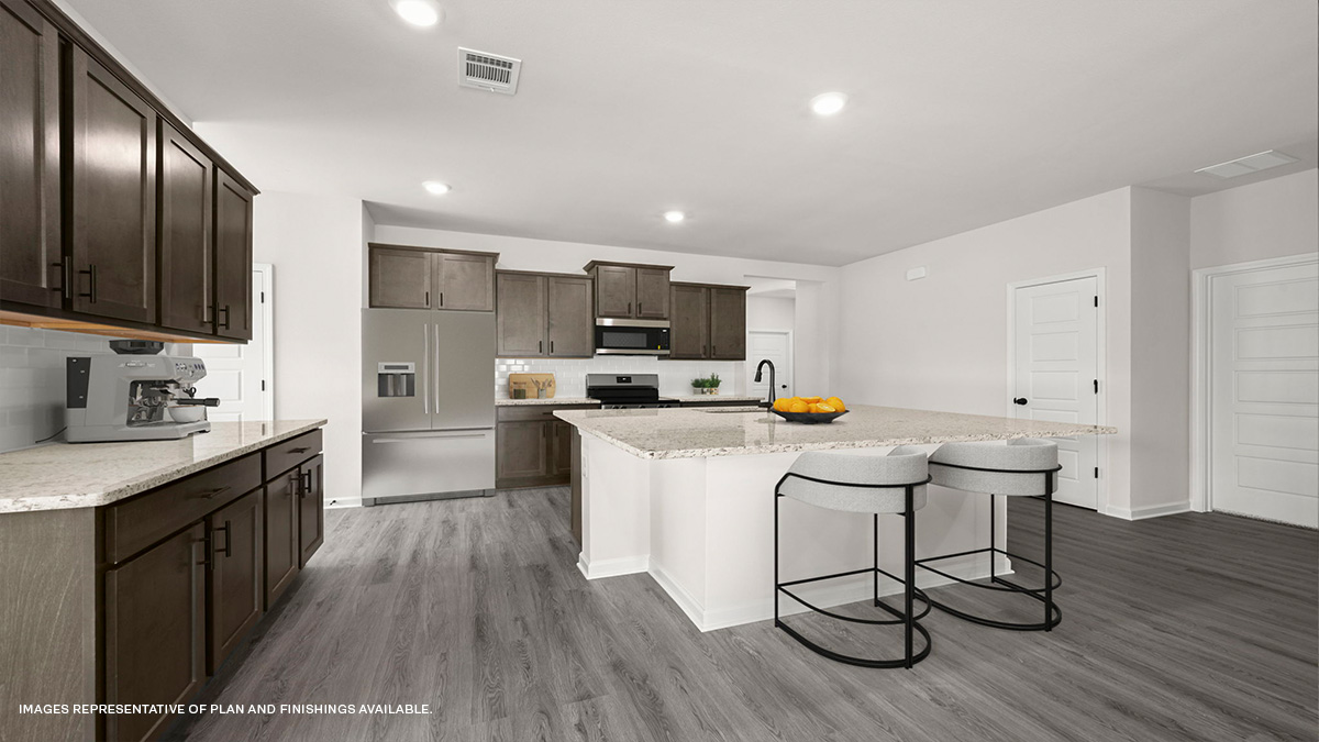 dark kitchen island with stainless steel appliances and open-concept living space in the rear
