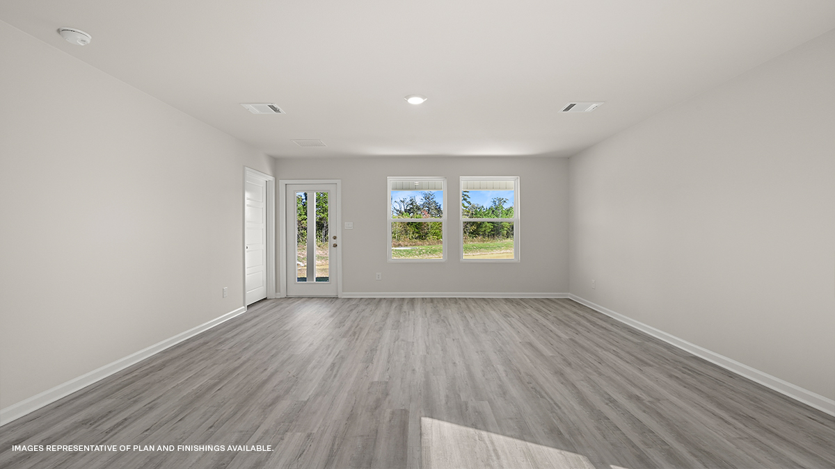 gray kitchen island with living and dining space in the with windows showcasing sun in the space