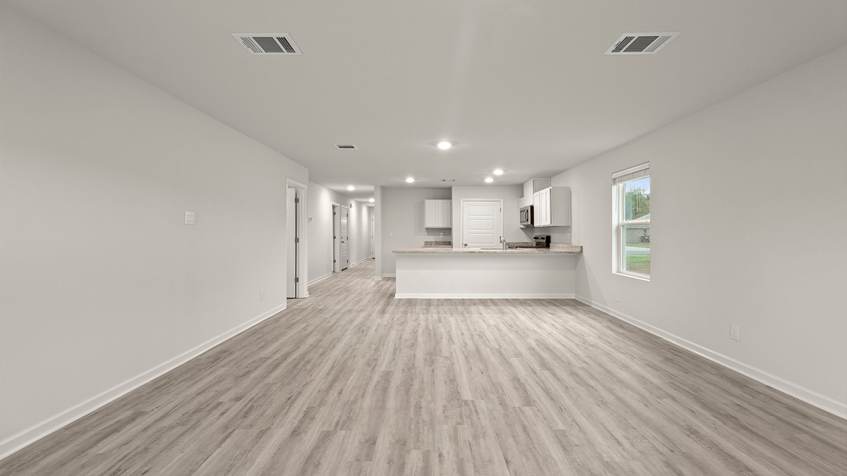 spacious living room with single side-view window with kitchen and dining space in the rear