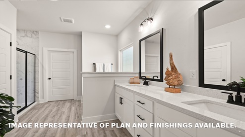 Dual vanities in primary bathroom with separate shower and closet access