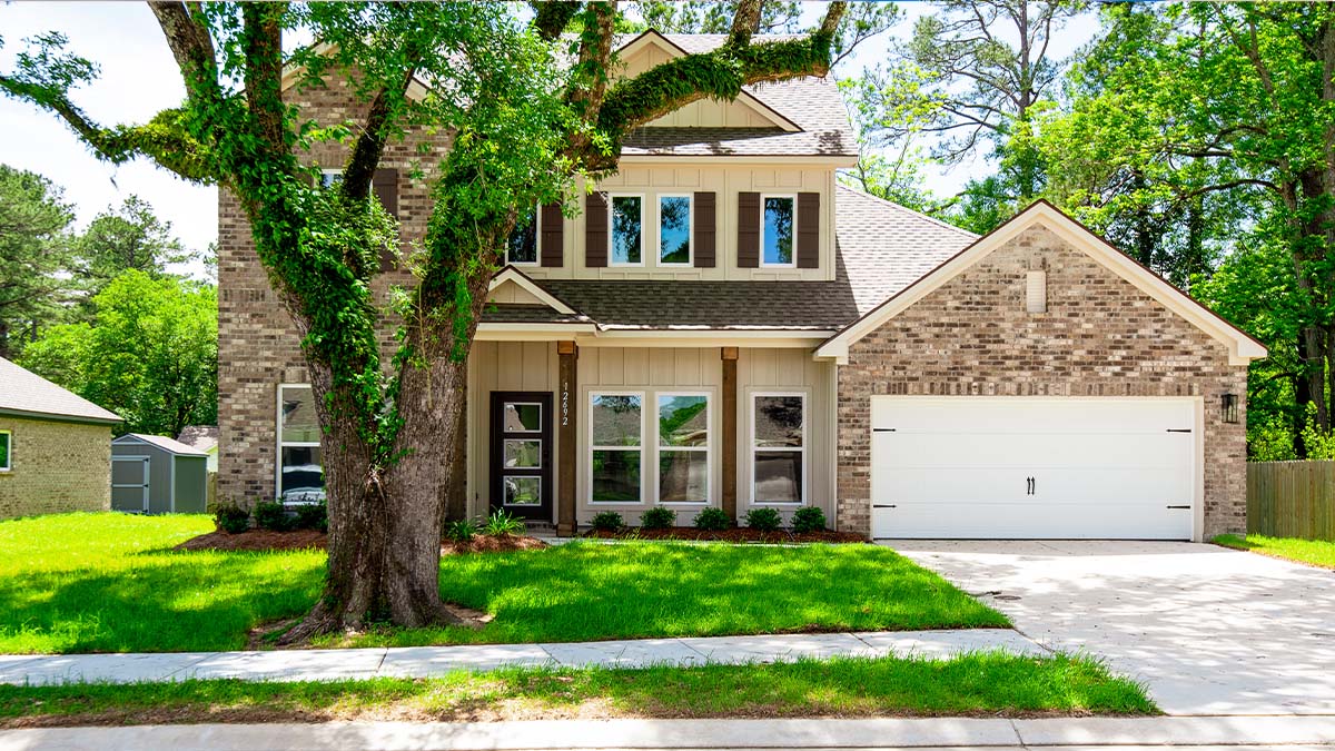 dual-story home with brown brick and tan hardi siding with brown front door and shutters with two-car garage